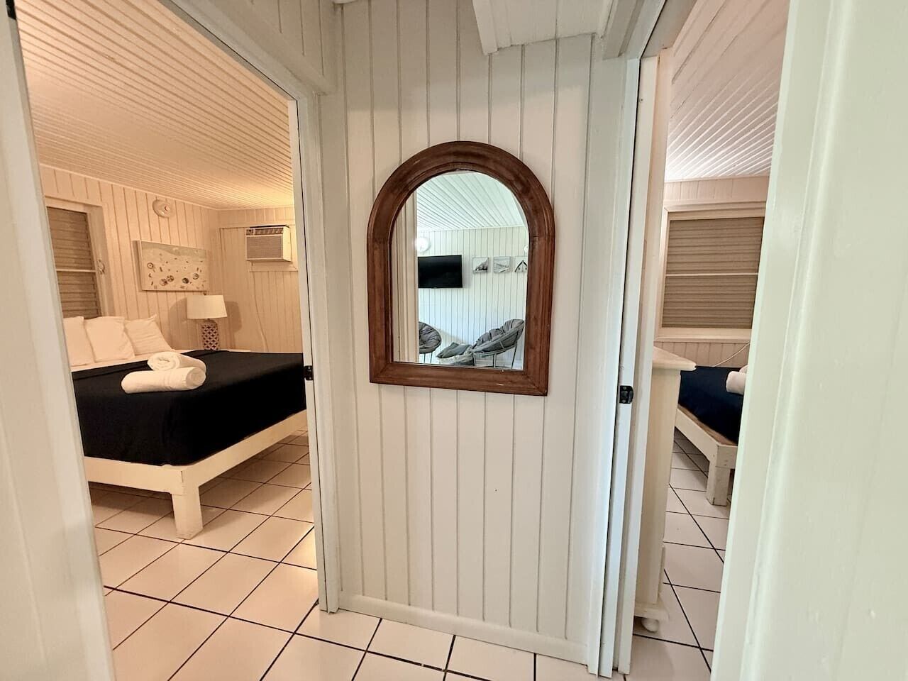 Een kamer met een bed, een tafeltje, een spiegel en een raam.