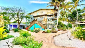 Ein Resort mit Holzterrasse, Palmen und einem Gebäude mit mehreren Balkonen.