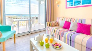 A room with a balcony, a striped sofa, a table with a teapot and fruit, and a wall with framed pictures. - Family Coastal Escape in the Vendee (Les Sables-d'Olonne)
