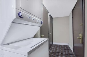 Un lavadero con lavadora y secadora de carga frontal, una puerta que da a otra habitación y un suelo estampado.