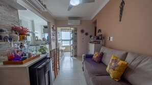 Een moderne keuken met een vaatwasser, een eethoek met stoelen, een bank met decoratieve kussens en een plafondventilator.