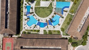 An aerial view of a resort with multiple swimming pools, a tennis court, and surrounding greenery. - Exclusive Oceanfront Bungalow with Included Service Eco Resort Carneiros (Praia dos Carneiros)