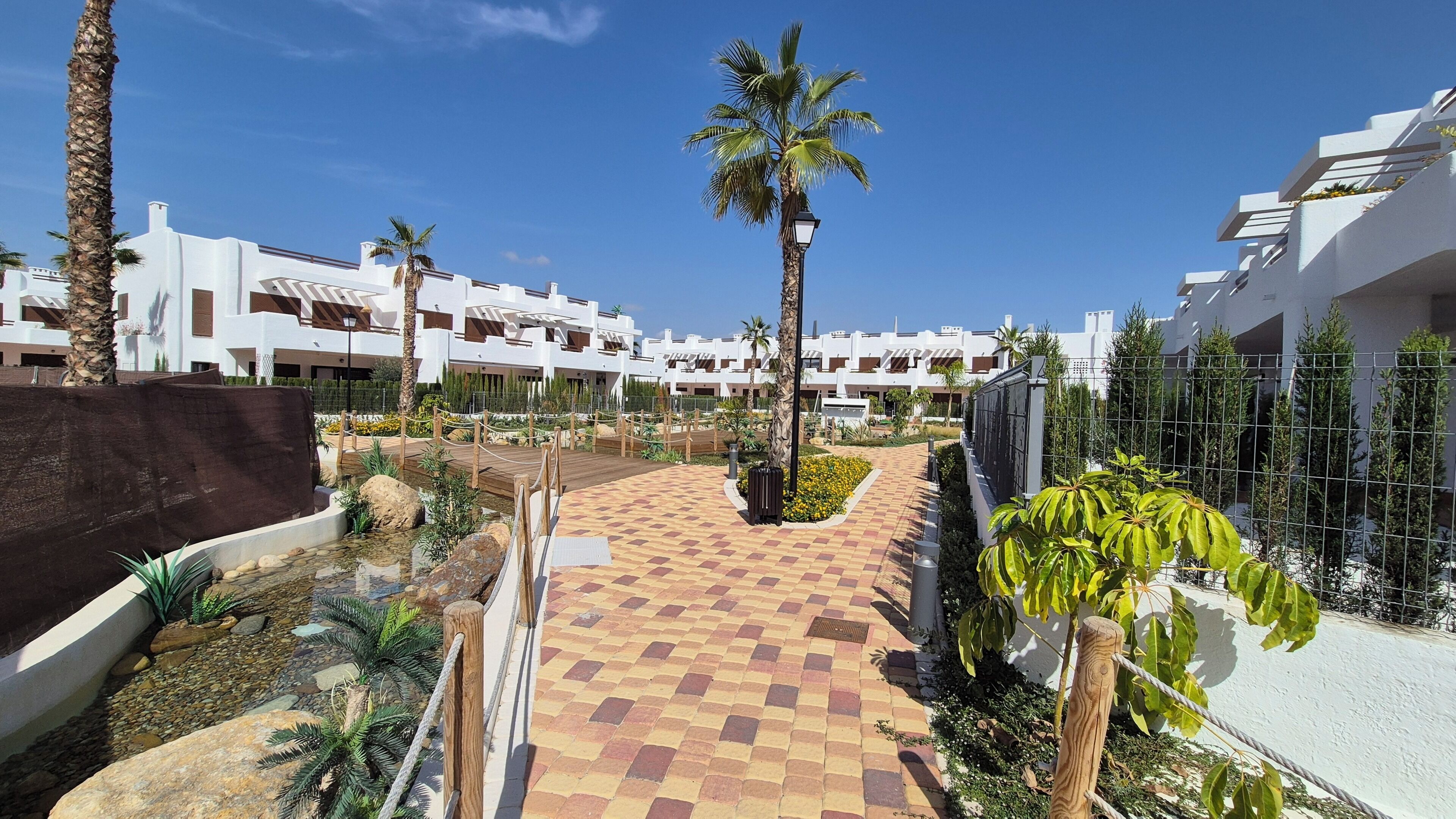 Ein Resort mit gepflastertem Weg, Palmen und modernen, weißen Gebäuden.