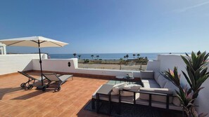A rooftop terrace with a white sofa, a table, and a stroller.