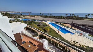 Un espace piscine sur le toit, comprenant plusieurs piscines, un patio avec des sièges et une vue sur la mer.