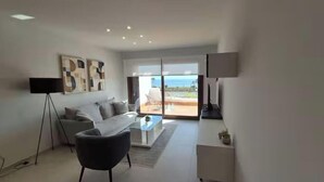 Un salon moderne avec un canapé, une table basse et une grande fenêtre donnant sur l’extérieur.
