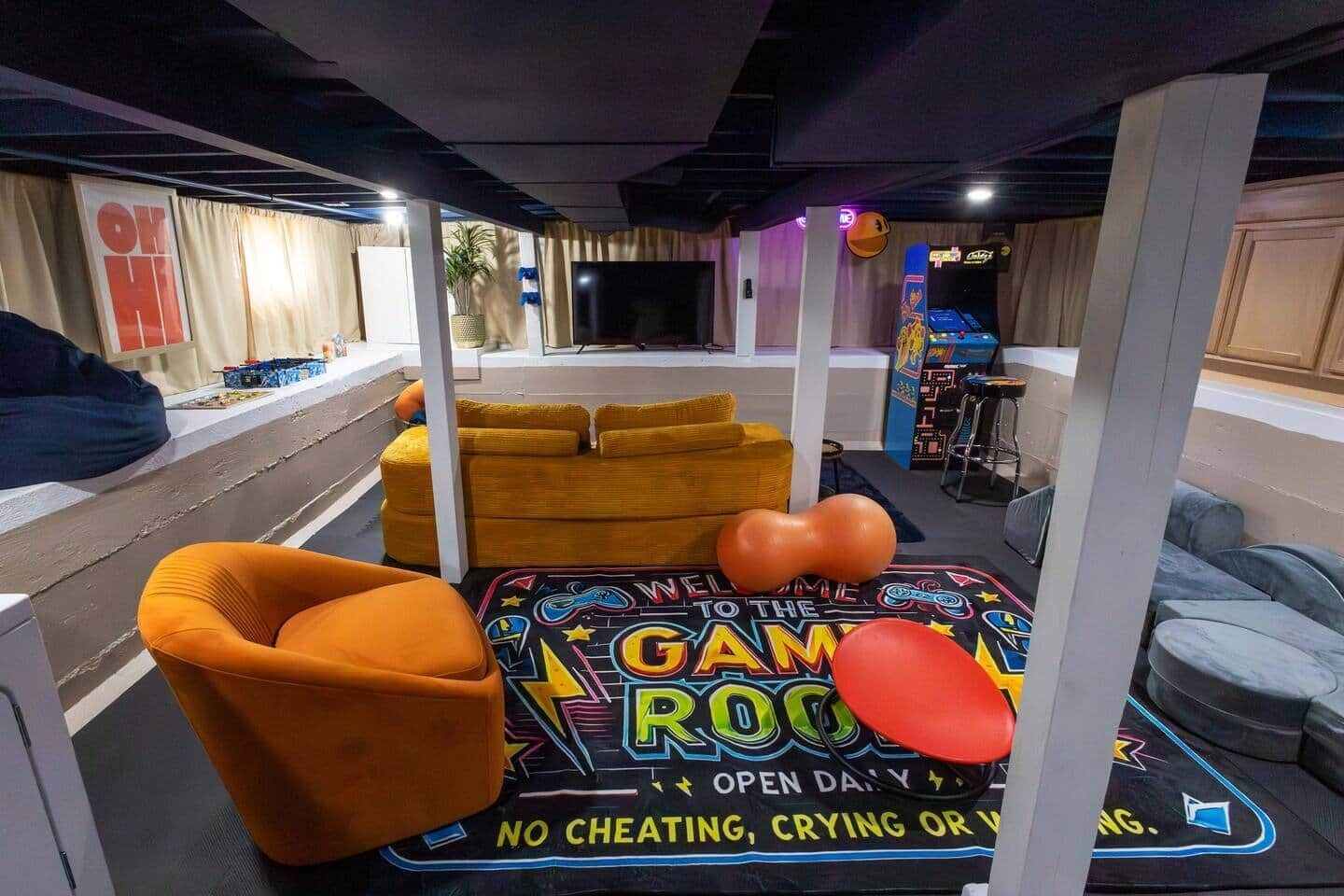 Een kamer met een speelhoek, inclusief een neonbord, een bank en een relaxfauteuil.