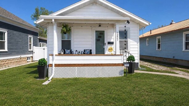 A single-story house with a front porch, a mailbox, and a 'hello' sign. - The Iris on Main | Game Room•Fenced Yard (Sheridan)