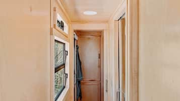 A narrow hallway with wooden walls, a window on the left, and a door on the right.