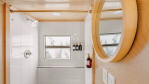 Un bagno con doccia, una finestra e uno specchio.