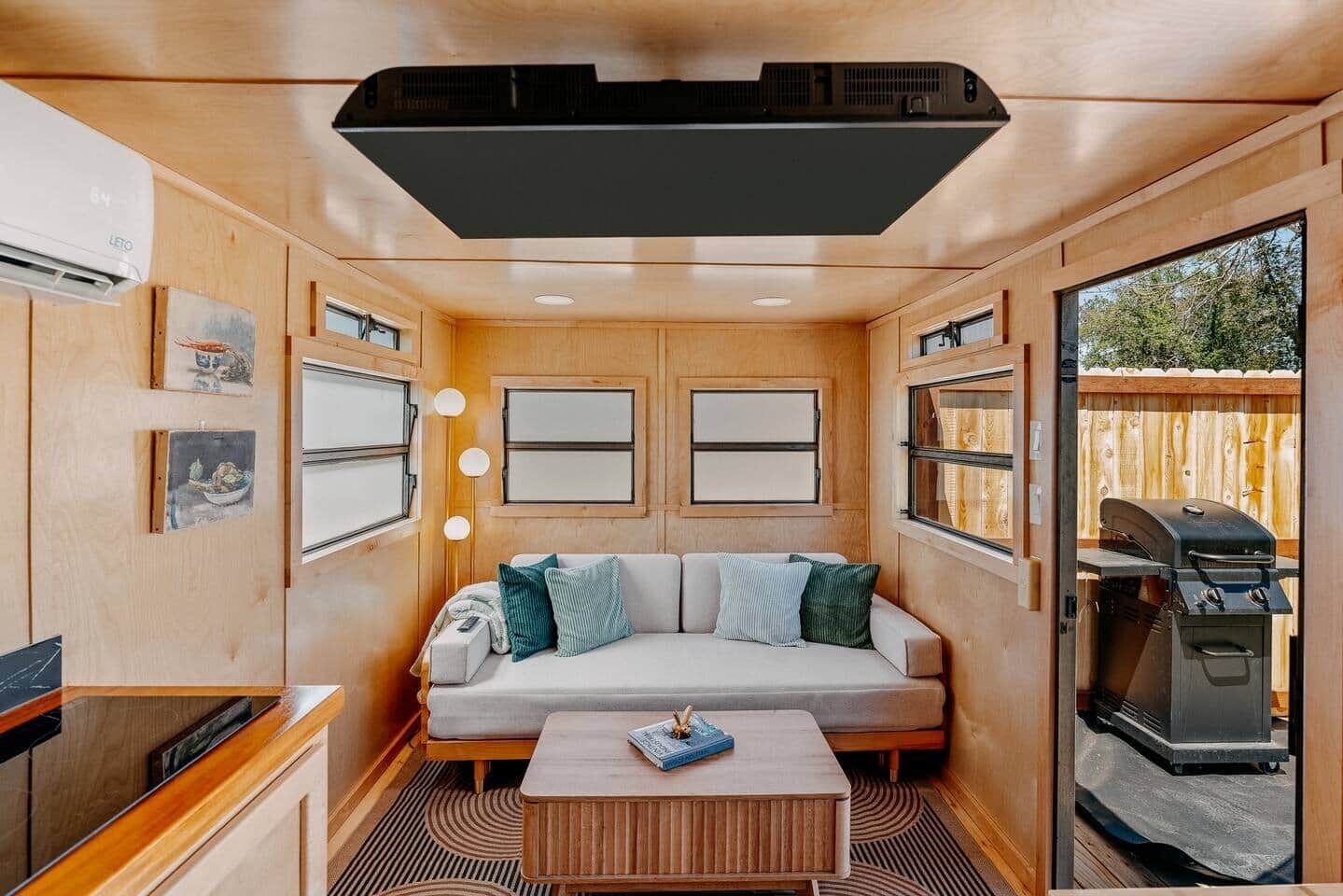 A cozy RV interior with a sofa, a coffee table, and a grill outside.