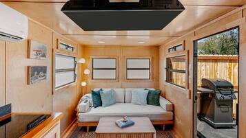 A cozy RV interior with a sofa, a coffee table, and a grill outside.