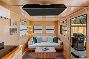 A cozy RV interior with a sofa, a coffee table, and a grill outside.