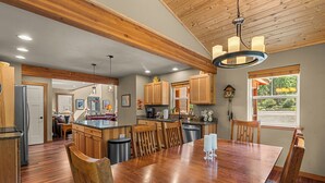 A spacious kitchen with wooden cabinets, a central island, and a dining area with a large wooden table and chairs.