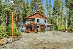 A two-story house with a porch, a garage, and a gravel driveway.