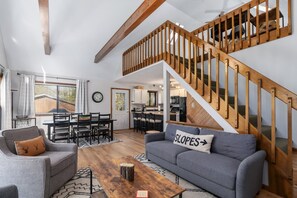 A modern living room with a grey sofa, wooden coffee table, and a staircase with wooden railings. - Superb 4-bedroom house with wrap around deck in charming Pocono Lake (Pocono Lake)