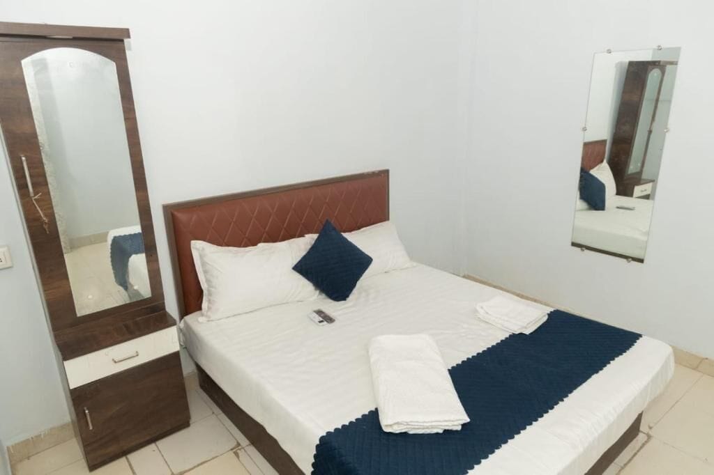 Un lit simple avec une tête de lit, un miroir de chevet et une armoire.