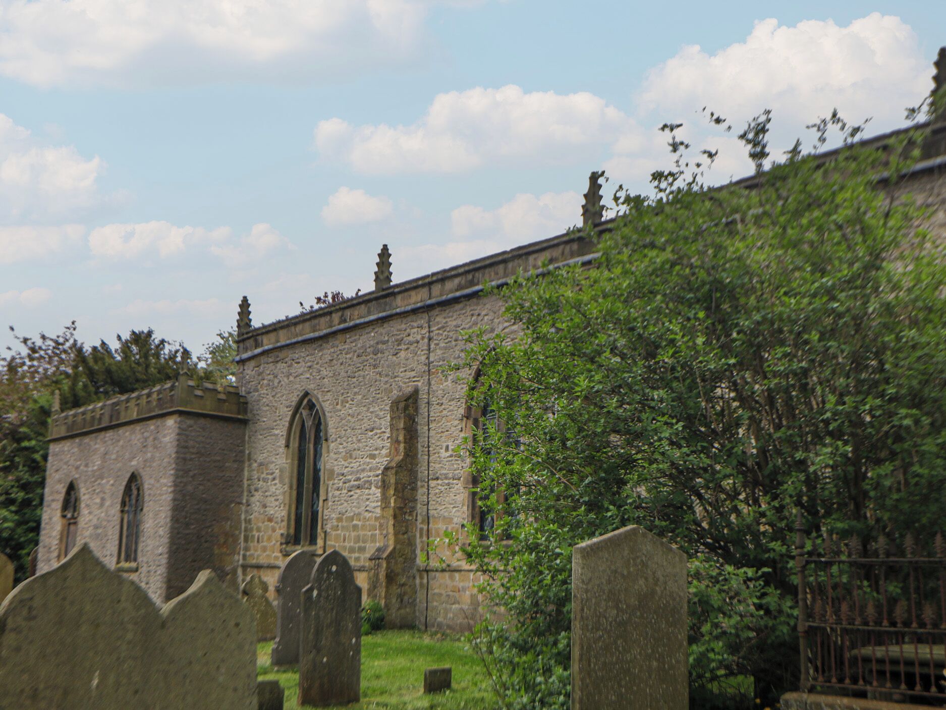 Une église en pierre, dotée de fenêtres en arc de cercle et d’un cimetière situé devant.