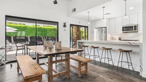 Une cuisine moderne avec un coin bar, des bancs en bois et une vue sur un jardin.