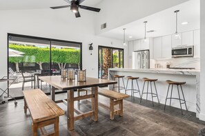 Eine moderne Küche mit Barbereich, Holzbänken und Blick auf einen Garten.