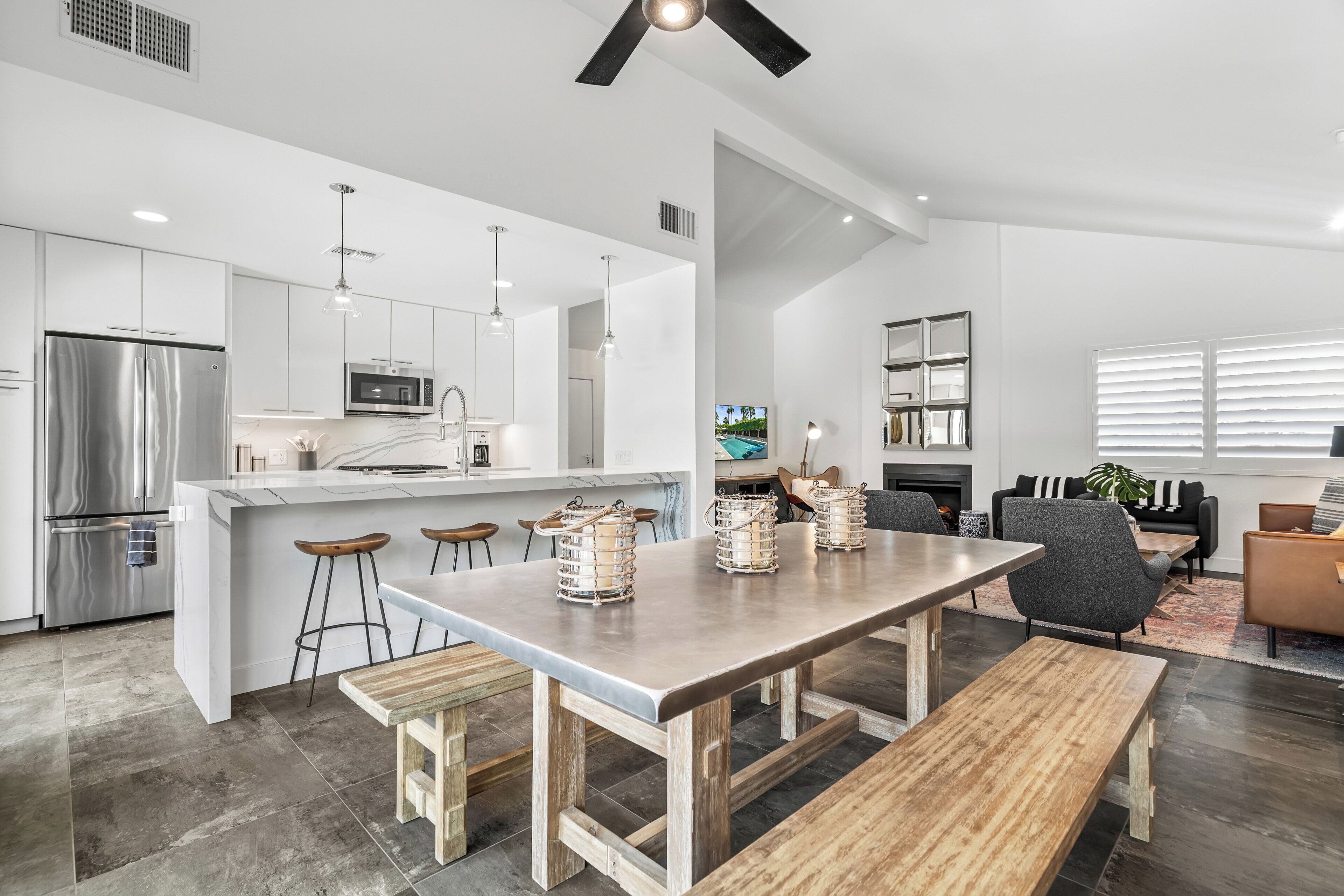 Una cocina moderna con una isla central, taburetes de bar y una mesa de comedor con bancos.