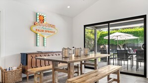 Un espace repas moderne avec une table et des bancs en bois, un panneau décoratif et une vue sur l’extérieur.