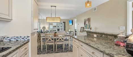 A modern kitchen with a dining area, granite countertops, and a large island.