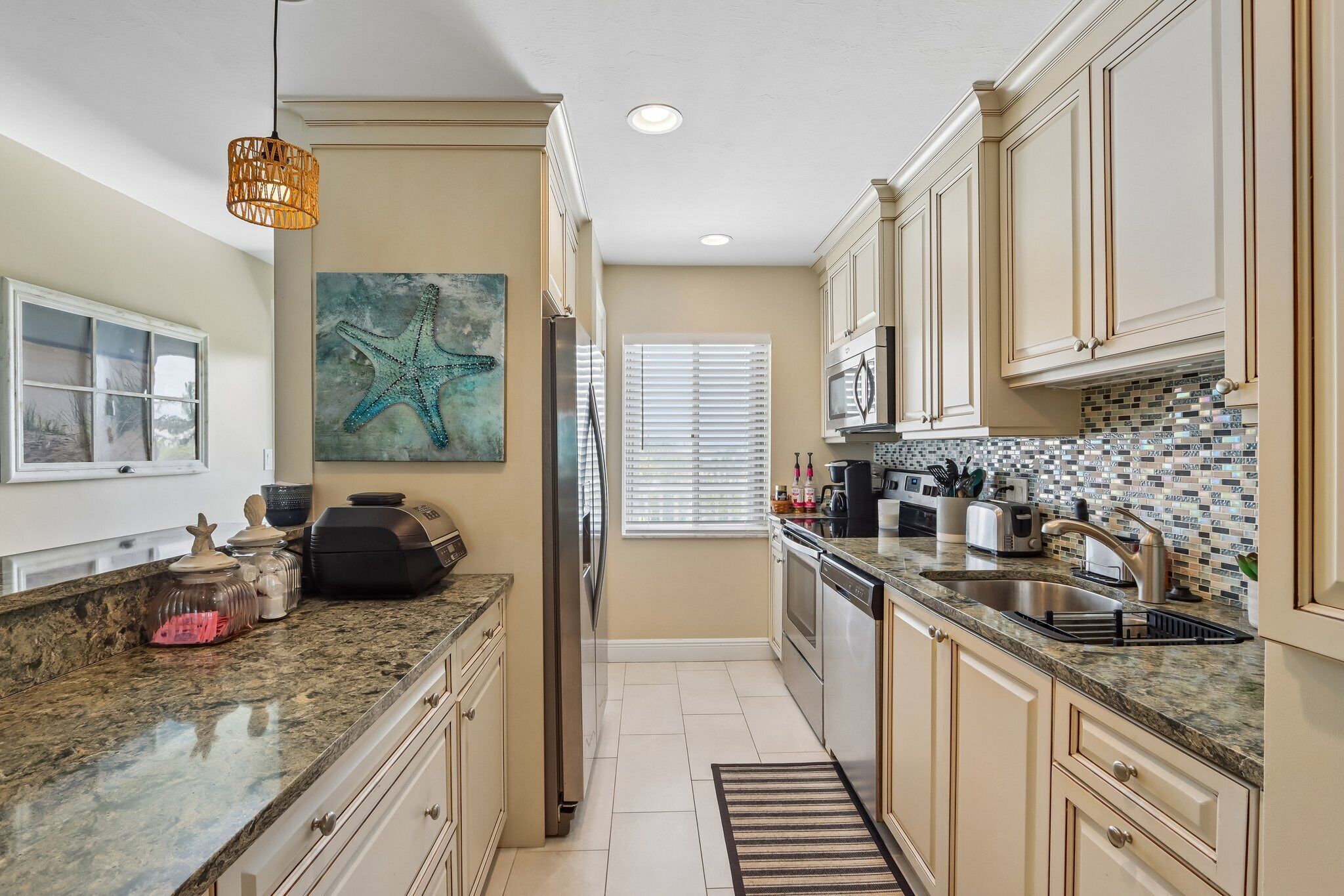 A kitchen with a granite countertop, stainless steel appliances, and a tiled backsplash.