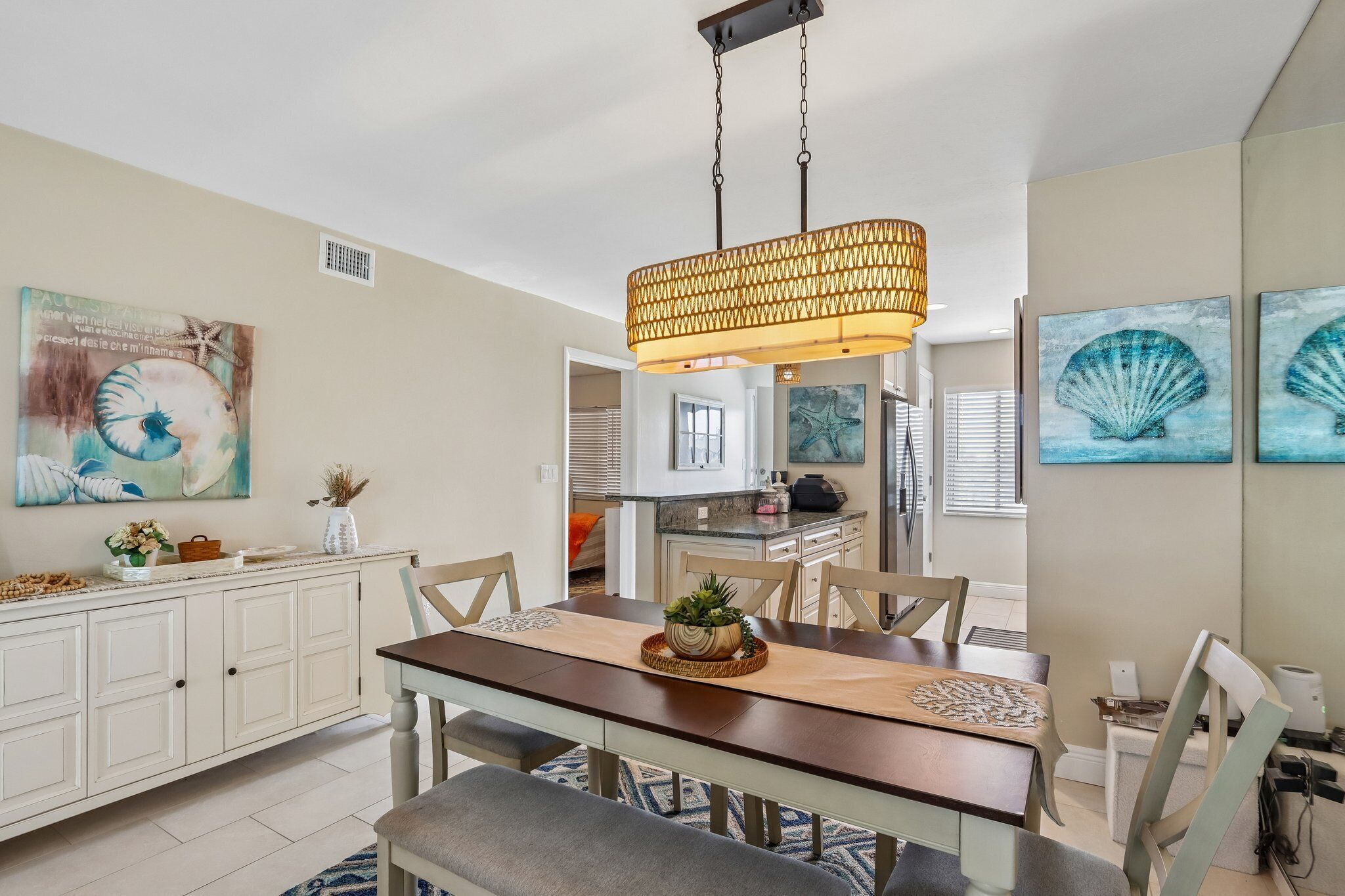 A dining area with a wooden table, chairs, a hanging light fixture, and artwork on the walls.