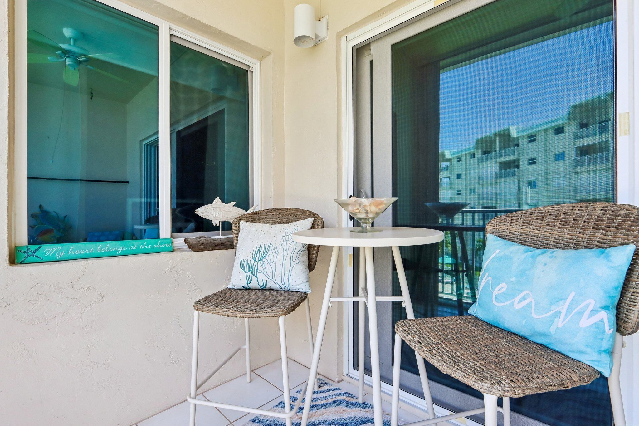 A balcony with wicker chairs, a small table, and a decorative fish sculpture.