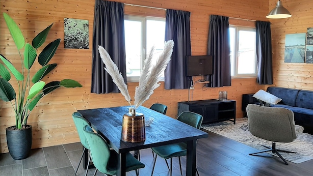 Un intérieur moderne avec un plafond en bois, une table à manger avec des chaises, un canapé et un téléviseur.