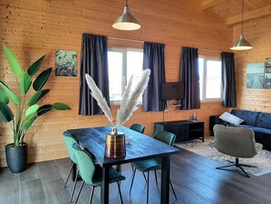 Un interior moderno con techo de madera, una mesa de comedor con sillas, un sofá y una televisión.
