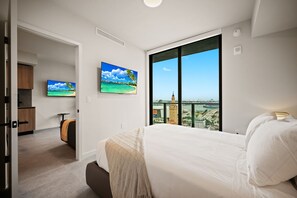 A hotel room with a large bed, a television, a painting, and a view of a cityscape. - Luxury Downtown Miami 501 First Rooftop Pool View (Miami)