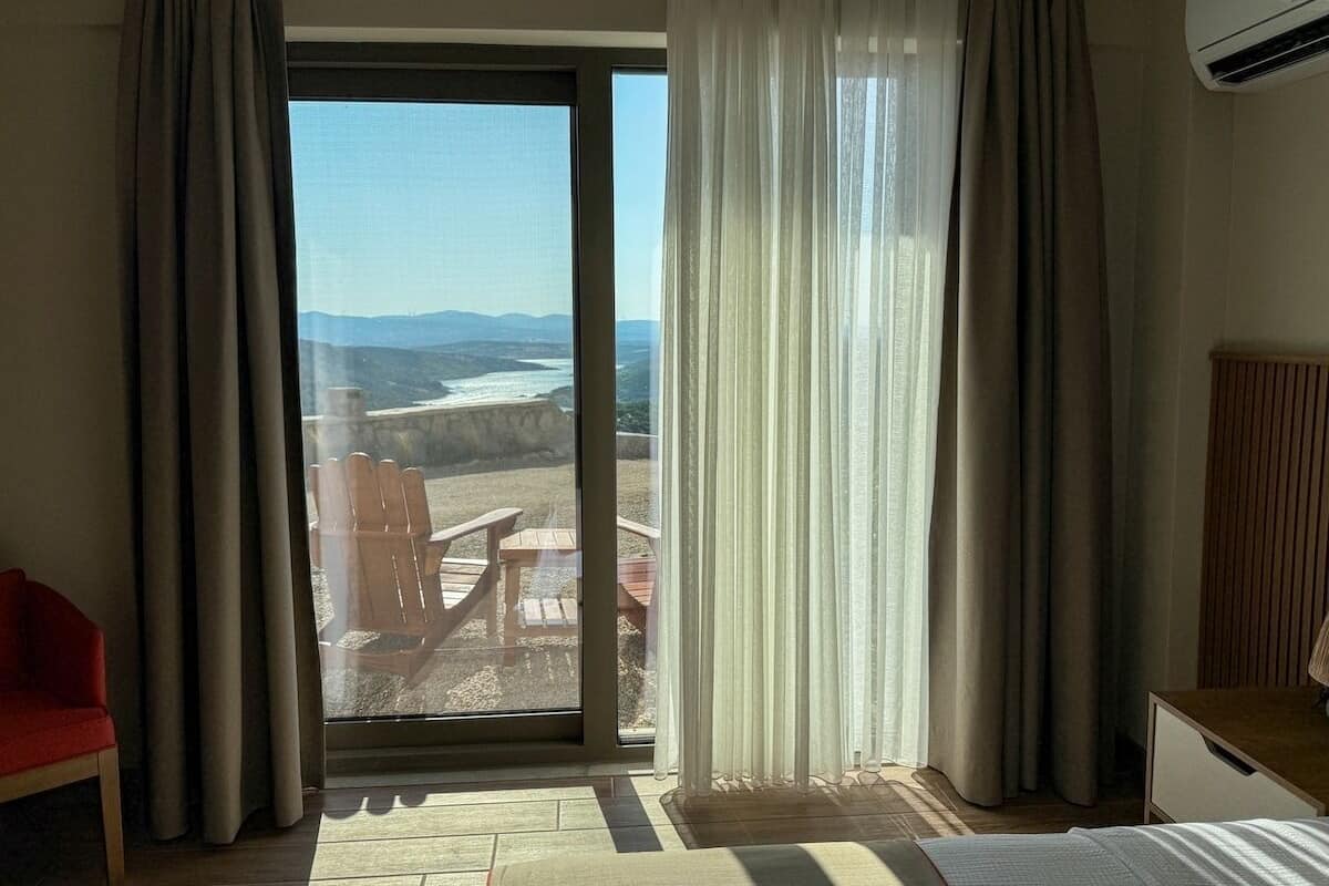 Una habitación con un amplio ventanal corredera que da a un área de estar exterior con vistas al océano.