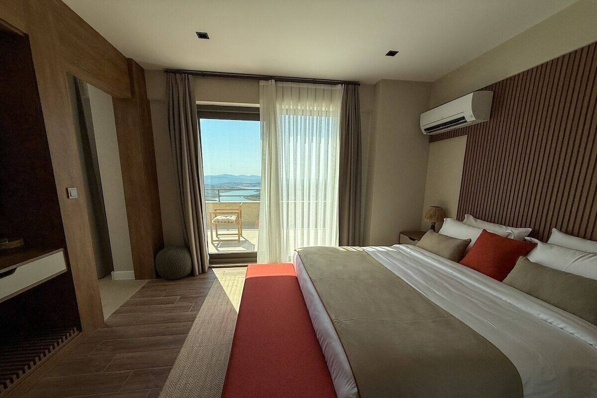 Una habitación de hotel con una cama grande, un balcón con vistas y un aire acondicionado.