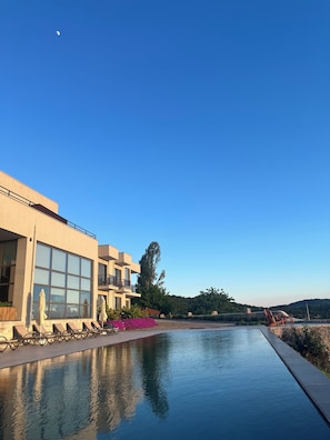 A modern building with large windows, a swimming pool, and outdoor seating. - Reya Kazdağları (Ayvacık)