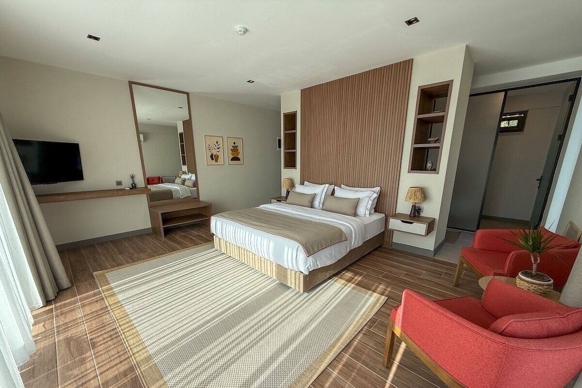 Habitación de hotel moderna con una cama grande, televisión, escritorio y una silla roja.