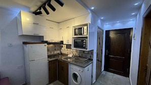 Cocina compacta con lavadora integrada, microondas y tostadora.