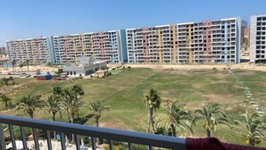Complejo residencial con varios edificios altos, una piscina y una zona ajardinada con palmeras.
