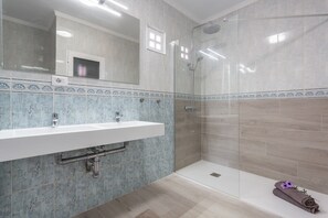 Une salle de bain avec une douche, un lavabo et un miroir.