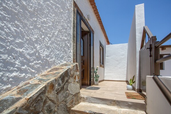 A stone staircase leading to a white-walled building with a tiled floor and a potted plant.
