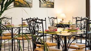 Ein Essbereich mit Metallstühlen und -tischen, einer Lampe und Kunstwerken an der Wand.