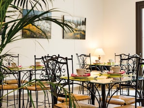A dining area with metal chairs, a glass table, and a lamp.