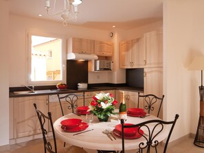 A dining area with a round table set for four, red plates, and a bottle of champagne.