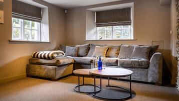 Una sala de estar acogedora con un sofá modular, una mesita redonda y un ventanal con vista a follaje.