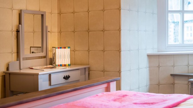 Ein Schlafzimmer mit einem Bett, einem Schminktisch, einem Spiegel und einem Fenster.