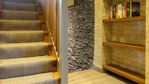 Eine Treppe mit einem strukturierten Teppich, einer Steinwand und einem Bücherregal mit Büchern und einem gerahmten Foto.