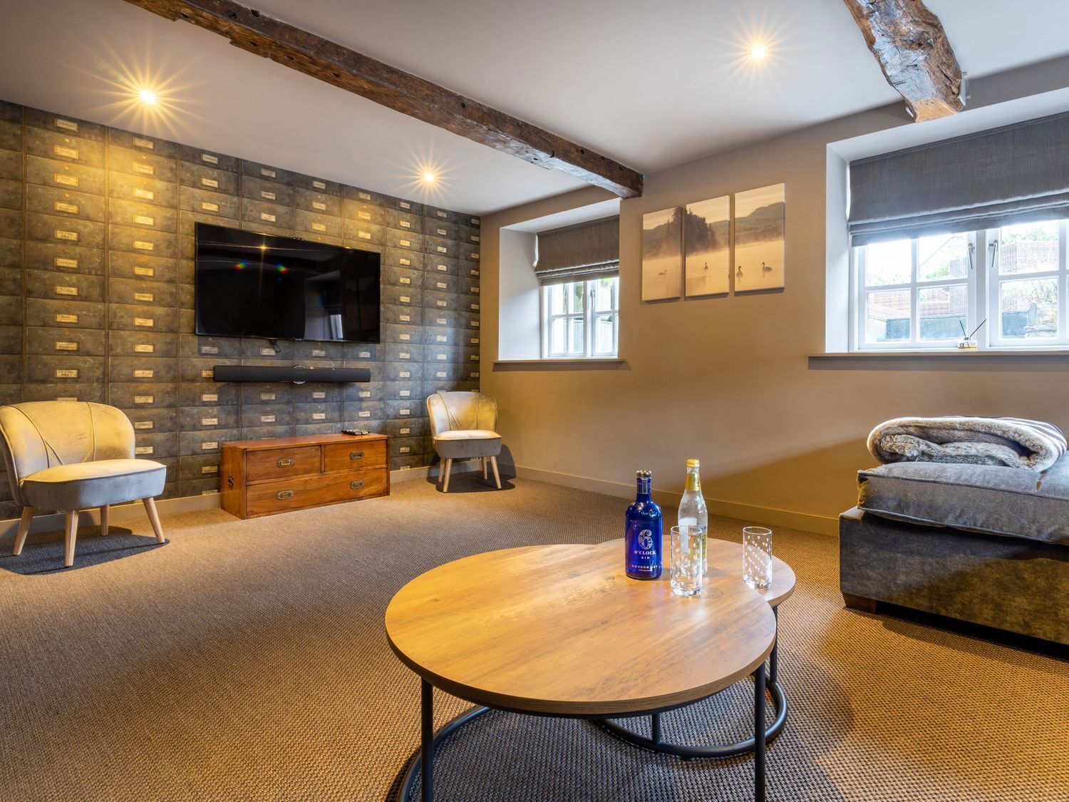 A modern living room with a stone wall, a flat-screen TV, a wooden coffee table, and a sofa.