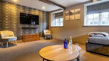 A modern living room with a stone wall, a flat-screen TV, a wooden coffee table, and a sofa.
