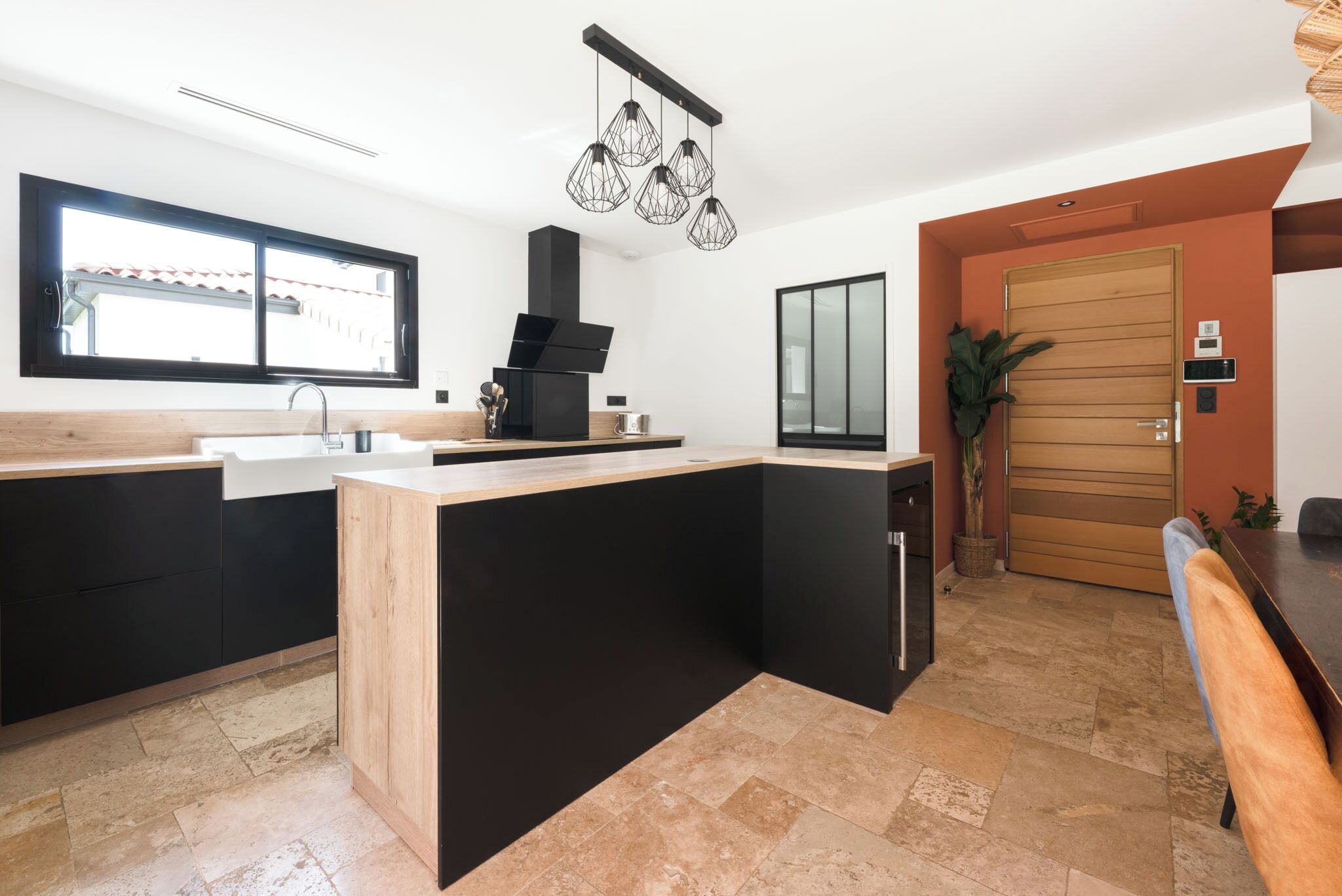 A modern kitchen with a black and wooden island, a built-in stove, and a large window.